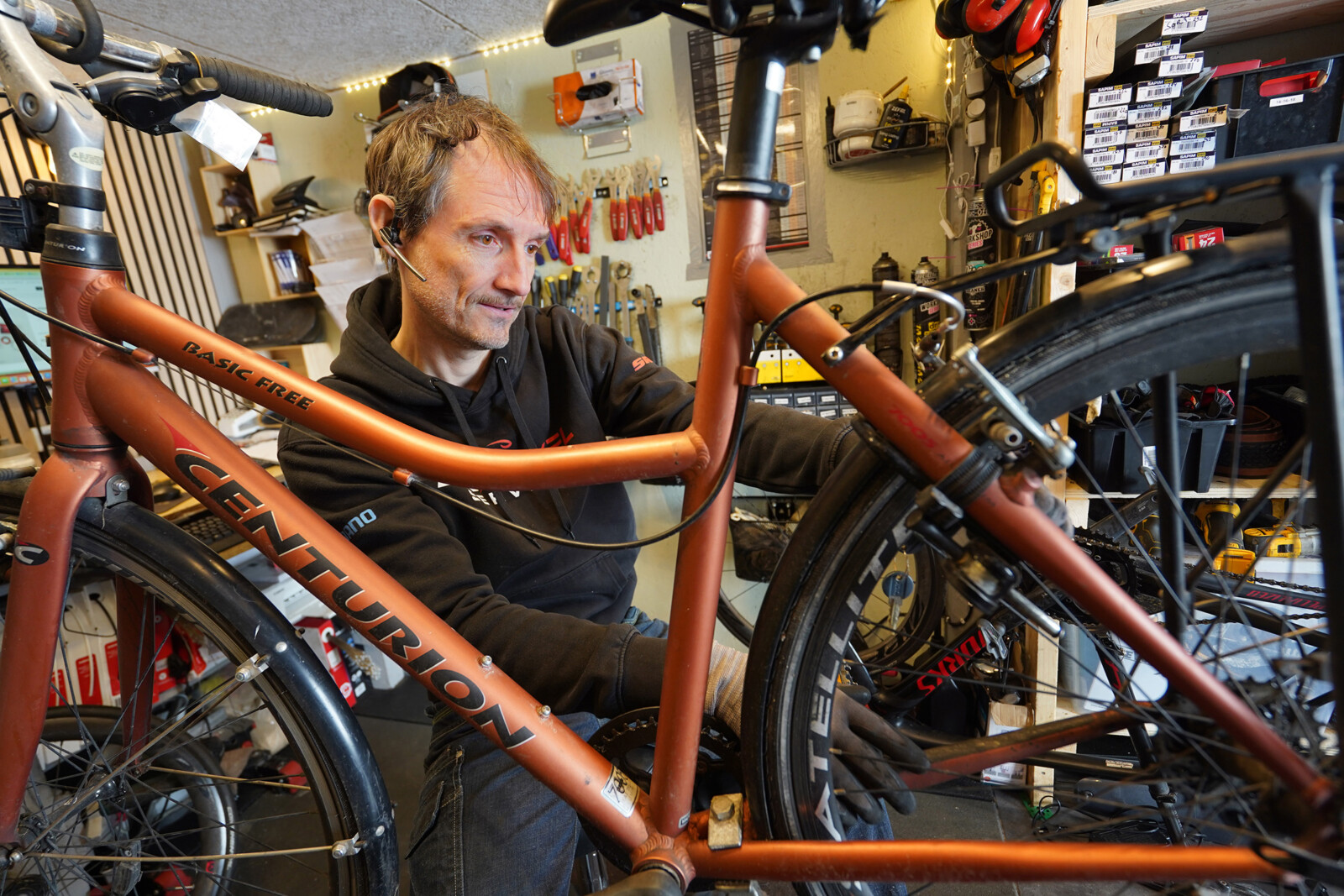 Cykelværksted. Cykelsmeden reparerer en ophængt orange cykel