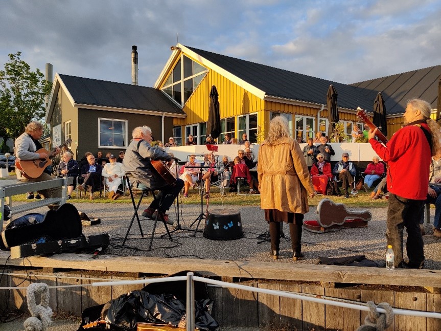 Kaløvig Bådehavn - Visesangere og musikere samt publikun, i baggrunden Kaløvig Badehotels gule træbygninger