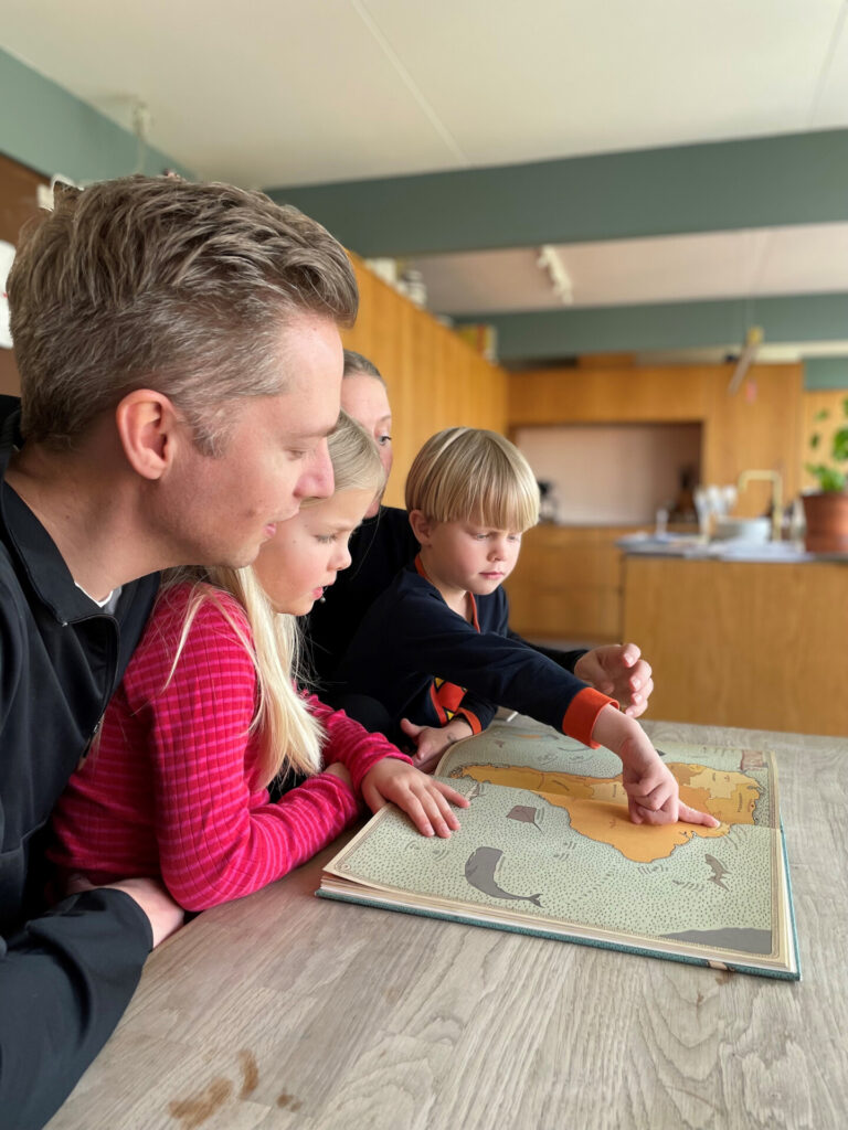 Familie ved bord med opslået verdenskort